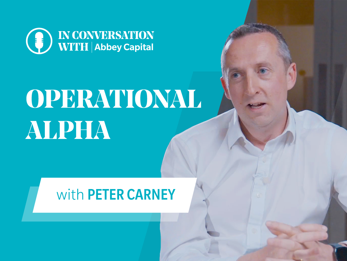 A man in a white shirt, identified as Peter Carney, speaks during an interview. On the left side of the image, Abbey Capital branding displays the text “In Conversation With Abbey Capital” and “Operational Alpha with Peter Carney.”